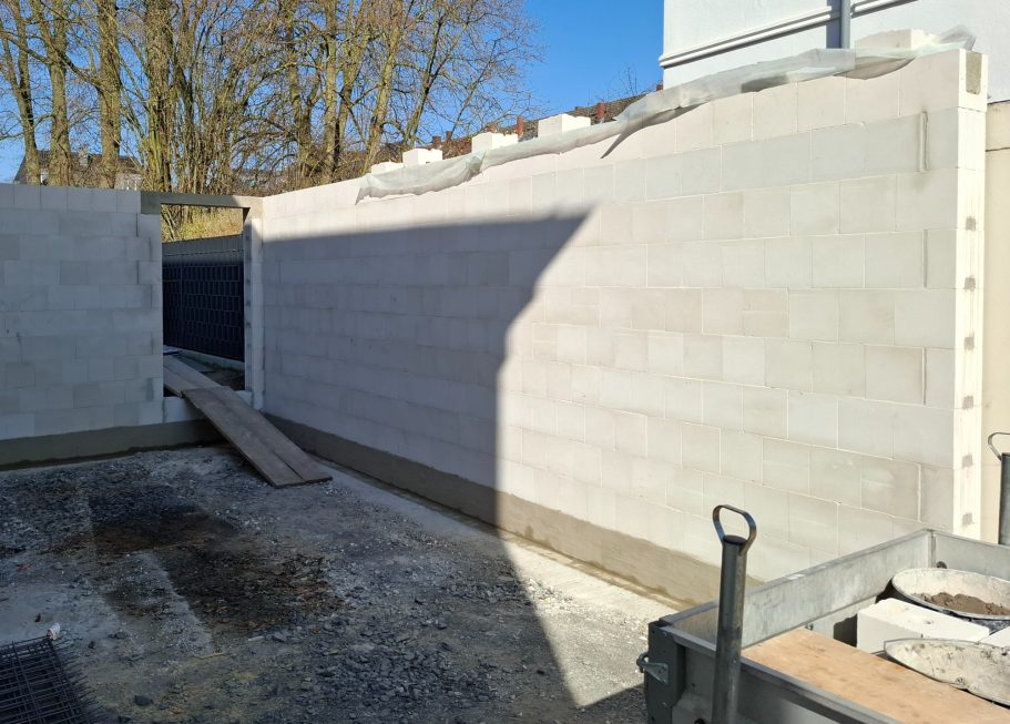 Wand aus Beton mit blauem Himmel im Hintergrund, Baugelände mit Materialien.